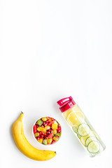 Weight loss concept. Fruit salad near fruit lemon and cucumber water on white background top view space for text