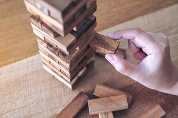 Closeup image of a hand holding and playing Tumble tower wooden block game