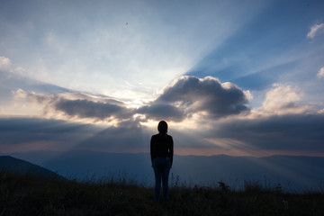 Obraz premium A woman standing and watching sunset with mountains view in the evening