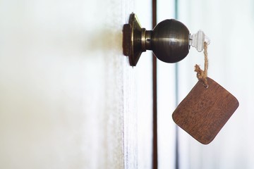 Home key with wooden blank house keychain in keyhole, property concept