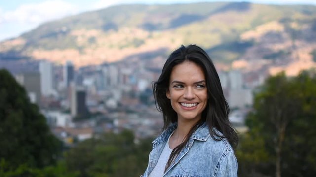Portrait of the beautiful smiling model girl in front of city panorama, Beautiful happy Caucasian tourist model smiling and posing in city park