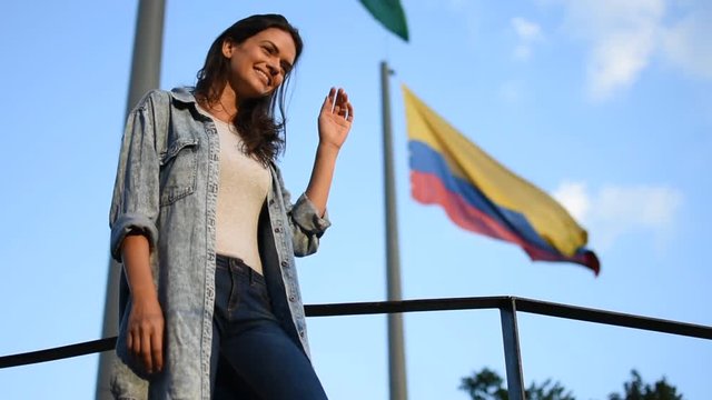 Proud happy woman in front of Colombian flag in Medellin, Beautiful young tourist woman smiling in front of the Colombian flag