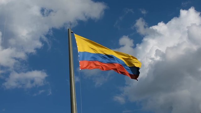Colombian flag moving strong and fast in front of the big clouds, Colombian national flag in dramatic sky and strong wind