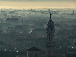 Bergamo, Italy. Amazing landscape of the town covered by the fog arising from the plain in fall season
