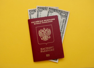 Russian passport with American dollars on the yellow background flat lay
