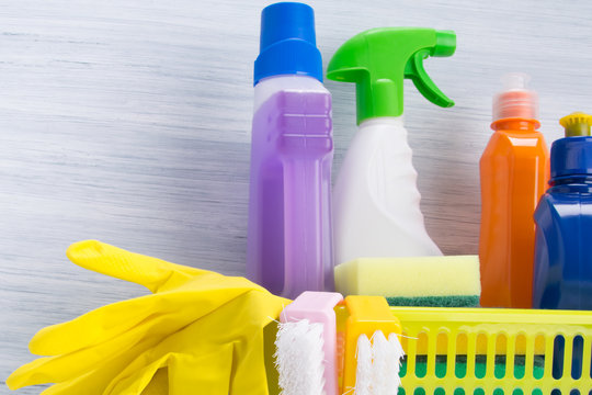 set of cleaning products, stands in a yellow basket, on a light background and yellow rubber gloves for cleaning