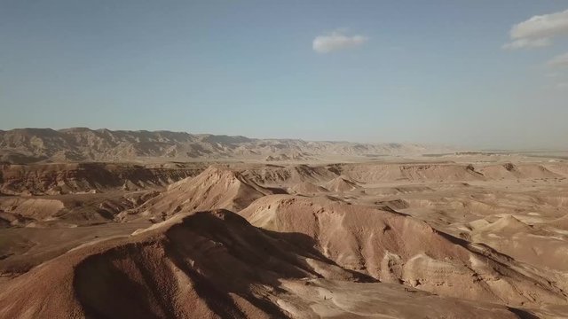 Israel Aerial Drone Of Middle Eastern Camel Owners In Desert Convoy Tourism. Flying View Edom Mountains Arava Rocky Desert with Sand sandy desert and clouds. kibbutz in southern Israel