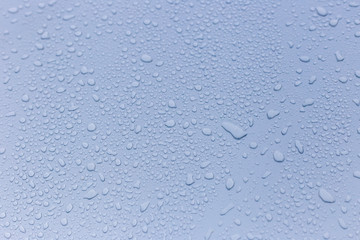 Wet rain drops on silver car hood. Abstract background. Water drops on red metal texture. Shallow focus, car body. Detail of red wet surface after rain 