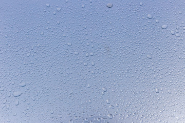 Wet rain drops on silver car hood. Abstract background. Water drops on red metal texture. Shallow focus, car body. Detail of red wet surface after rain 