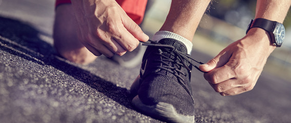 Running shoes - closeup of man tying shoe laces. - obrazy, fototapety, plakaty