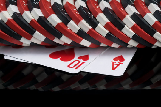 two red poker cards lie under casino chips on a black background