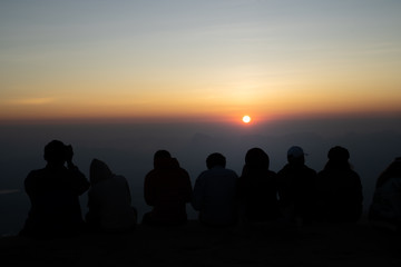 Fototapeta na wymiar Image of black silhouette of people watching the sunrise on colorful horizon