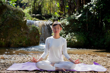 Beautiful girls are playing yoga at the park. Among the natural waterfalls in the forest, exercise concepts