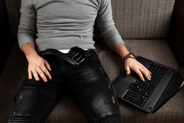 A man watches an adult video on a laptop while sitting on the couch. The concept of porn, men's...