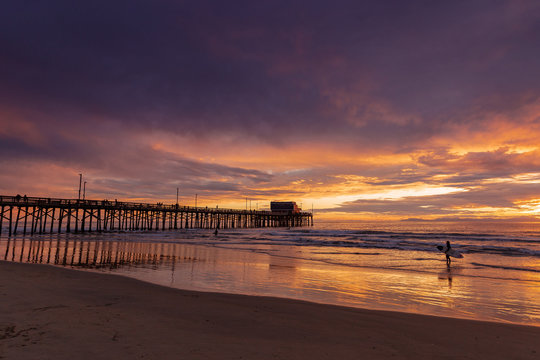 surfer and pier with beautiful sunset