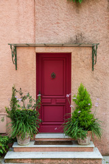 Fototapeta na wymiar Red door with plants in the medieval village of Eze in southeastern France