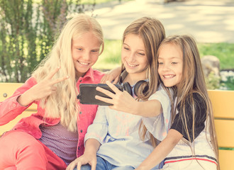 Girls making selfie outdoors while sitting on longboards