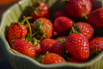 Fresh strawberries in a bowl in warm sunset light macro