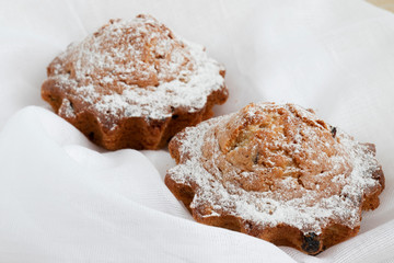 Two freshly baked muffins with raisins on a white napkin