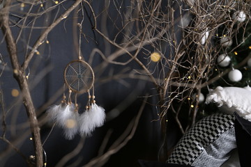 Dreamcatcher and branch trees against the background of a green fir-tree with white spheres and pieces of multi-colored pillows