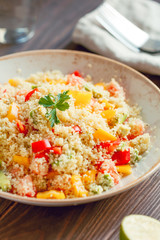 Couscous salad with fresh red and yellow bell peppers, avocado, tomatoes and lime. The concept of vegetarian and healthy food.