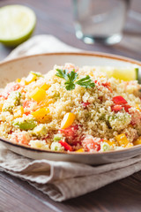 Couscous salad with fresh red and yellow bell peppers, avocado, tomatoes and lime. The concept of vegetarian and healthy food.