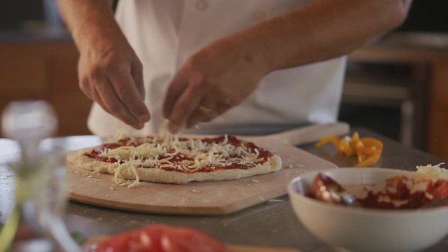 Chef adds mozzarella cheese to pizza
