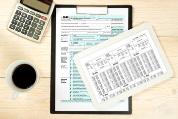 1040 tax form and tax tables on white wooden table