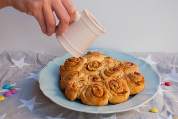 Woman water cinnamon roll pie with glaze. Homemade bakery.