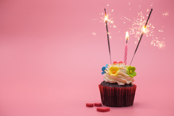 cupcake with sparkler on pink background