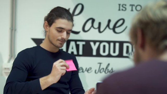 Funny colleague joked over an serious employee, sticking an obscene language on a sticker on his clothes