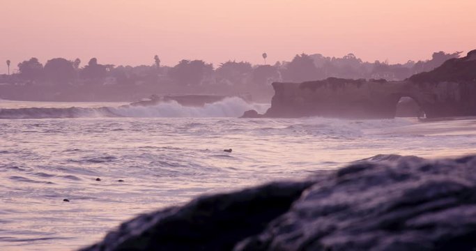 Surfer swims for wave and misses it durning sunset - practice perseverance