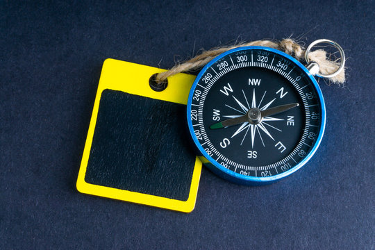 Wooden tag and compass on black background with selective focus and crop fragment. Business and motivation concept