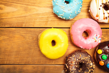 Many delicious donuts on the wooden table