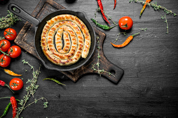 Fried sausage in a pan with garlic, tomatoes and herbs.