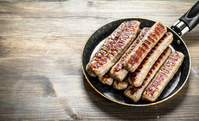 Fried sausages in a frying pan.