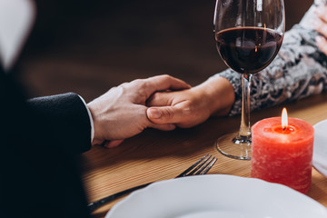 Middle-aged loving couple holding hands at a table in a restaurant close-up