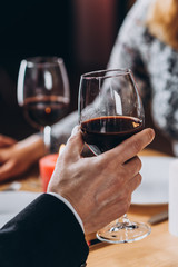 Loving couple have a romantic dinner. Man raising a glass with red wine close-up