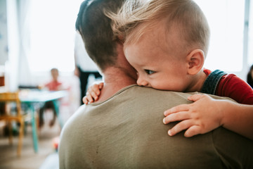 Father carrying his son into a classroom