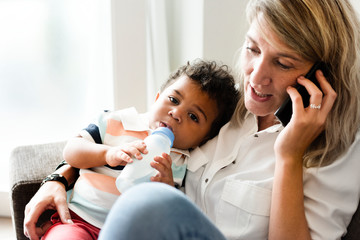 Mother feeding her baby while on the phone