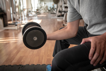 Fototapeta na wymiar closeup of young athlete Man exercising with dumbbell in fitness studio - Image