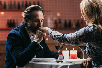 Man makes a marriage proposal and kisses the hand of a woman in a restaurant