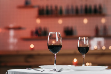 Two glasses with red wine on a served table in a restaurant close-up. Romantic atmosphere, blurred background
