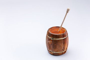 Wooden open barrel with fragrant liquid honey and honey stick on a white background. Close-up.