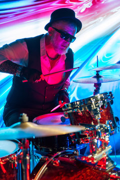 Drummer playing on drum set on stage in the color light