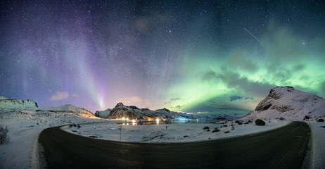 Aurora borealis with starry over mountain range on arctic coastline