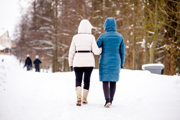 Two women walk along the path in the winter Park