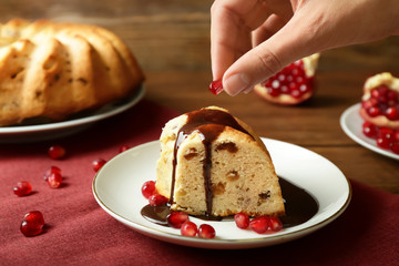 Woman decorating piece of Christmas cake with pomegranate seeds
