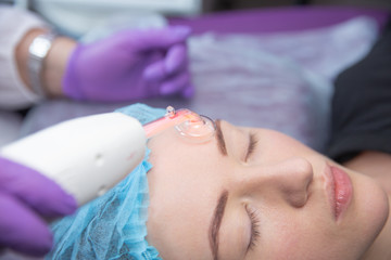 Receiving electric darsonval facial massage procedure at beauty salon