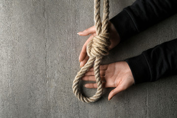 Female hands and rope with loop on grey background. Suicide concept